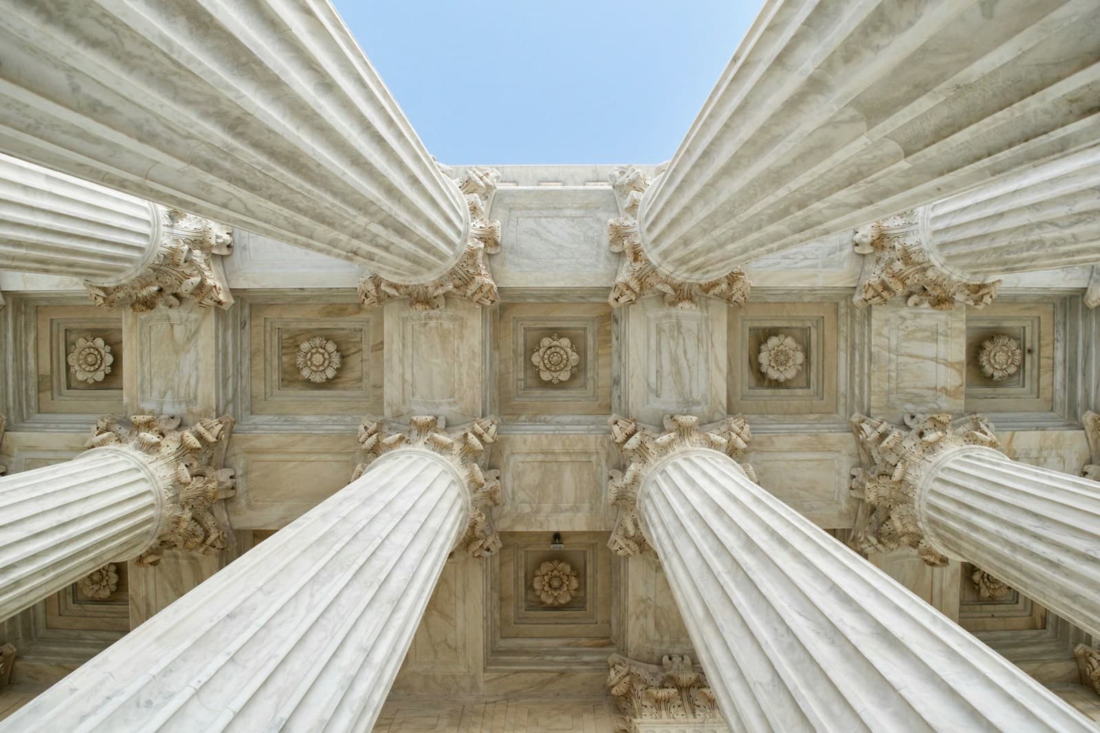 Marble columns and a carved stone ceiling at the entrance of a court building